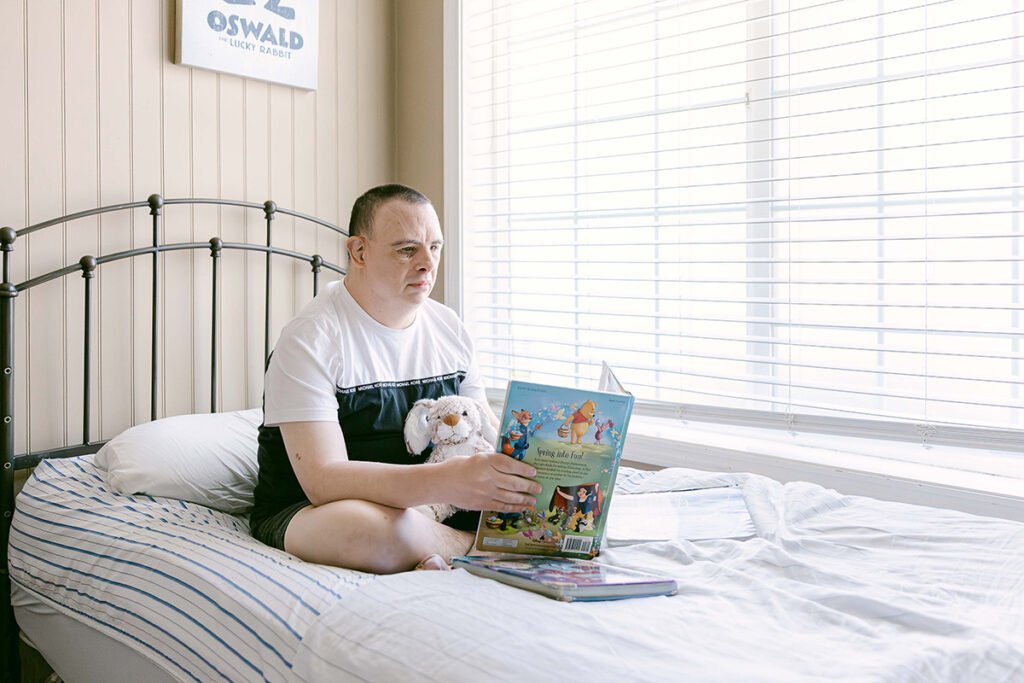 Individual with disability reading a book in their bedroom